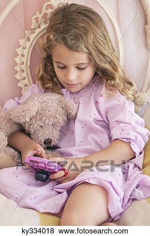 Cute little girl playing video game on the bed View Large Photo Image Stock Photo - Cute little girl playing video game on the bed. Fotosearch