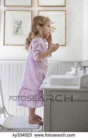 Cute little girl standing on a chair in front of a bathroom sink View Large Photo Image Stock Image - Cute little girl standing on a chair in front of a bathroom sink. Fotosearch