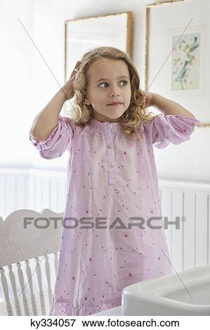 Cute little girl standing on a chair in front of a bathroom sink View Large Photo Image Stock Photo - Cute little girl standing on a chair in front of a bathroom sink. Fotosearch