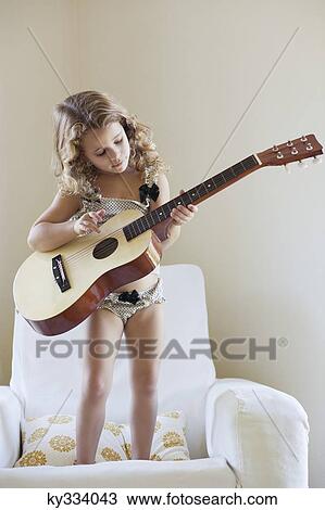 Cute little girl standing on a sofa and playing a guitar View Large Photo Image Stock Image - Cute little girl standing on a sofa and playing a guitar. Fotosearch