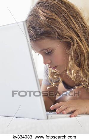Cute little girl using a laptop in the bed View Large Photo Image Stock Image - Cute little girl using a laptop in the bed. Fotosearch