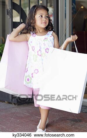 Cute little girl walking out of a shopping mall with shopping bags View Large Photo Image Stock Photograph - Cute little girl walking out of a shopping mall with shopping bags. Fotosearch