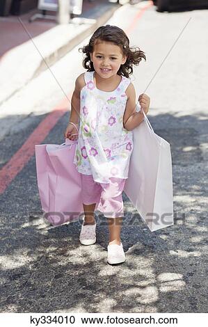 Cute little girl walking with shopping bags in hands View Large Photo Image Stock Image - Cute little girl walking with shopping bags in hands. Fotosearch