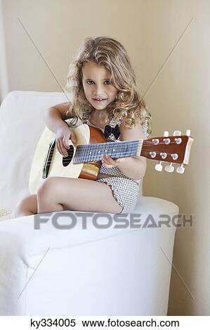 Portrait of a cute little girl playing a guitar View Large Photo Image Stock Photography - Portrait of a cute little girl playing a guitar. Fotosearch