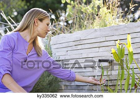 Beautiful young woman with hand under flowing water View Large Photo Image Stock Image - Beautiful young woman with hand under flowing water. Fotosearch