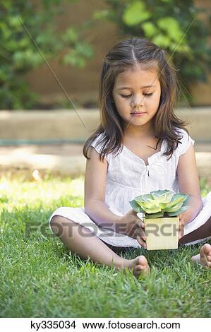 Picture - Cute little girl holding a potted plant. Fotosearch