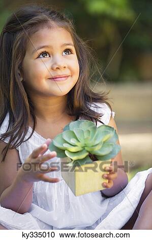 Cute little girl holding a potted plant and looking up View Large Photo Image Stock Image - Cute little girl holding a potted plant and looking up. Fotosearch