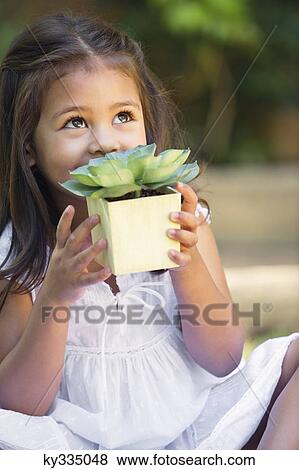 Cute little girl holding a potted plant and looking up View Large Photo Image Stock Photo - Cute little girl holding a potted plant and looking up. Fotosearch