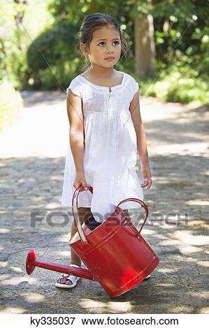 Cute little girl holding a watering can View Large Photo Image Stock Photo - Cute little girl holding a watering can. Fotosearch