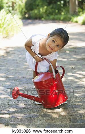 Cute little girl picking up a watering can View Large Photo Image Stock Photograph - Cute little girl picking up a watering can. Fotosearch