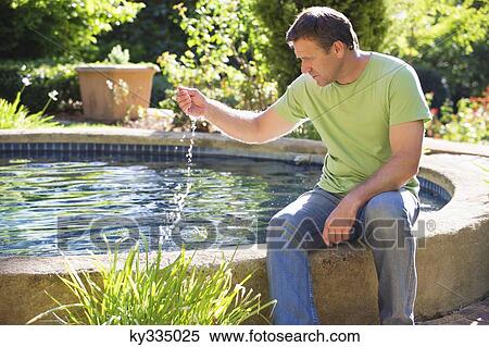Stock Photography - Mature man sitting at the poolside. Fotosearch