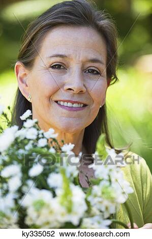 Portrait of a woman holding a bunch of flowers outdoors View Large Photo Image Stock Image - Portrait of a woman holding a bunch of flowers outdoors. Fotosearch