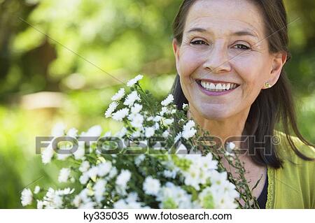 Stock Photography - Portrait of a woman holding a bunch of flowers outdoors. Fotosearch