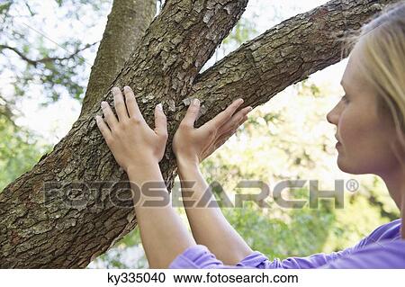Side profile of a young woman touching tree branch View Large Photo Image Stock Image - Side profile of a young woman touching tree branch. Fotosearch