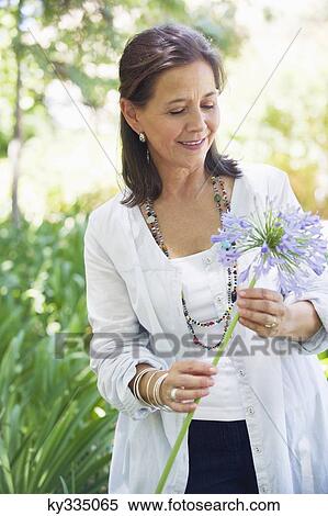 Smiling woman holding a single flower in hand View Large Photo Image Stock Photography - Smiling woman holding a single flower in hand. Fotosearch
