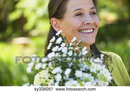 Stock Photo - Woman holding a bunch of flowers outdoors. Fotosearch