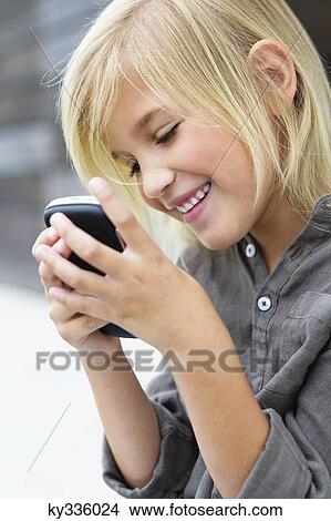 Close-up of a girl using a mobile phone and smiling View Large Photo Image Picture - Close-up of a girl using a mobile phone and smiling. Fotosearch