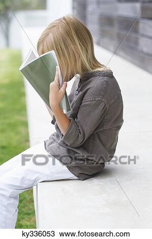 Girl holding a book in front of her face View Large Photo Image Stock Image - Girl holding a book in front of her face. Fotosearch
