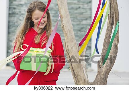 Girl holding a gift box and smiling View Large Photo Image Stock Image - Girl holding a gift box and smiling. Fotosearch