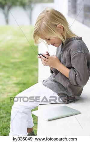 Girl text messaging with a mobile phone View Large Photo Image Stock Photo - Girl text messaging with a mobile phone. Fotosearch
