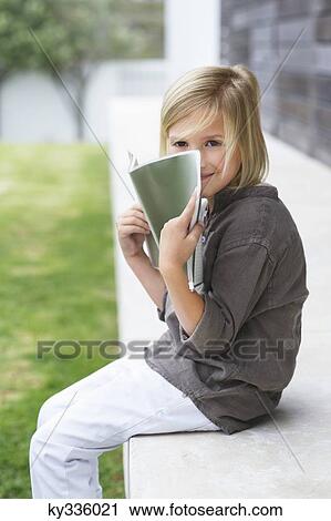 Portrait of a girl holding a book and smiling View Large Photo Image Stock Image - Portrait of a girl holding a book and smiling. Fotosearch