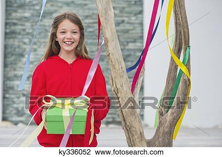 Stock Image - Portrait of a girl holding a gift box and smiling. Fotosearch