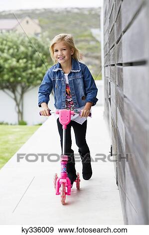 Portrait of a smiling girl riding a push scooter View Large Photo Image Stock Photo - Portrait of a smiling girl riding a push scooter. Fotosearch