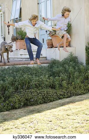 Two little children jumping in air with dog in the background View Large Photo Image Stock Photo - Two little children jumping in air with dog in the background. Fotosearch