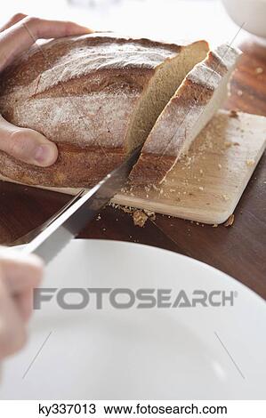 Close-up of a person's hand cutting bread View Large Photo Image Stock Image - Close-up of a person's hand cutting bread. Fotosearch