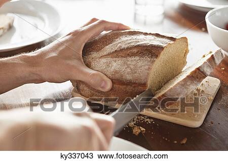 Close-up of a person's hand cutting bread View Large Photo Image Stock Image - Close-up of a person's hand cutting bread. Fotosearch