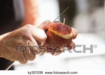 Stock Photo - Close-up of man's hand peeling an apple. Fotosearch