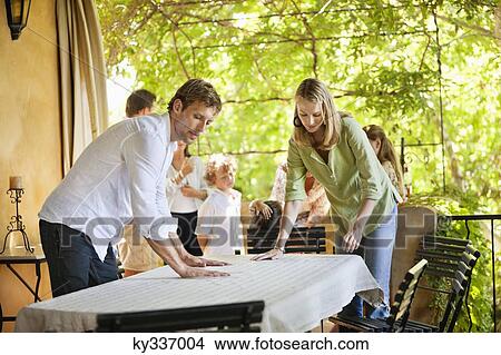 Couple preparing dining table for meal time View Large Photo Image Picture - Couple preparing dining table for meal time. Fotosearch