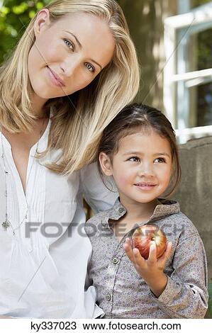 Daughter holding apple with mother smiling View Large Photo Image Stock Image - Daughter holding apple with mother smiling. Fotosearch
