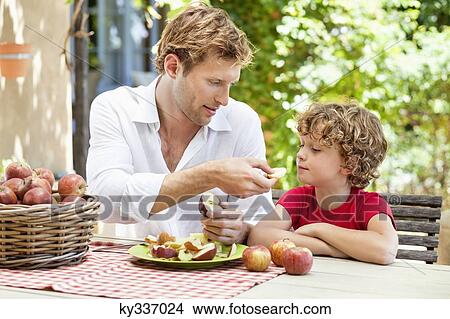 Father feeding apples to his son View Large Photo Image Picture - Father feeding apples to his son . Fotosearch
