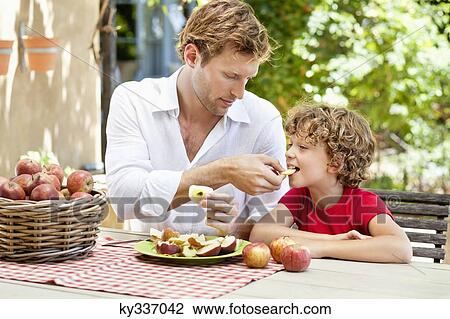Father feeding apples to his son View Large Photo Image Stock Image - Father feeding apples to his son . Fotosearch