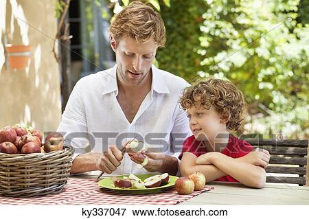 Stock Photo - Father peeling apple with son . Fotosearch