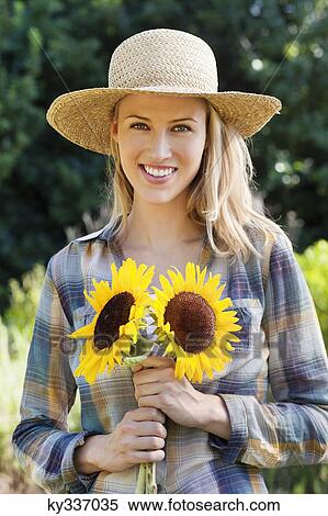 Portrait of a young woman holding sunflowers in a field View Large Photo Image Stock Photography - Portrait of a young woman holding sunflowers in a field. Fotosearch