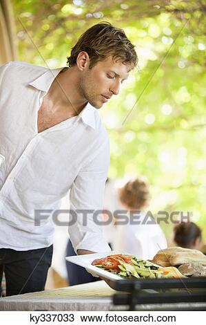 Young man serving salad View Large Photo Image Stock Image - Young man serving salad. Fotosearch