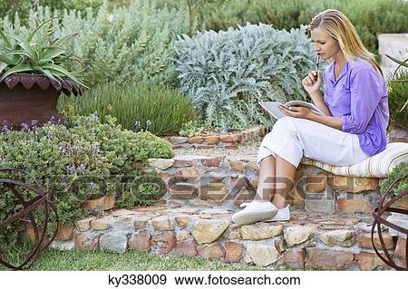 Beautiful young woman reading book in garden View Large Photo Image Stock Photo - Beautiful young woman reading book in garden. Fotosearch