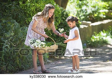 Girl giving flower to her little sister View Large Photo Image Stock Image - Girl giving flower to her little sister. Fotosearch
