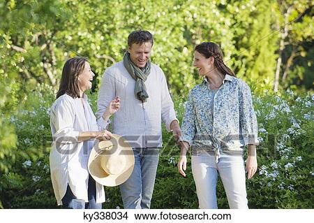 Picture - Happy mature couple standing with their mother in a garden. Fotosearch