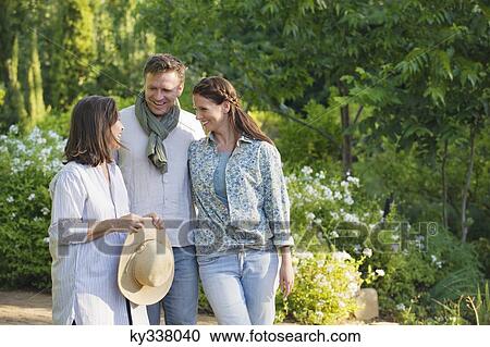 Stock Image - Happy mature couple standing with their mother in a garden. Fotosearch