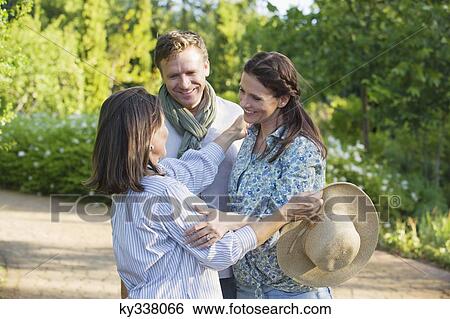 Stock Photograph - Happy mature couple standing with their mother in a garden. Fotosearch