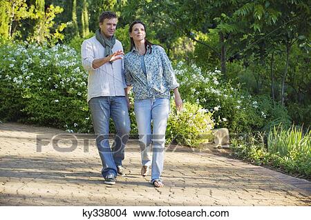 Happy mature couple walking in a garden View Large Photo Image Picture - Happy mature couple walking in a garden. Fotosearch