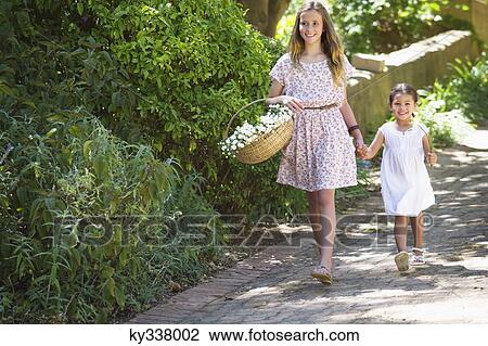 Happy siblings walking holding hands in garden View Large Photo Image Stock Image - Happy siblings walking holding hands in garden. Fotosearch