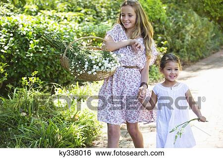 Happy siblings walking holding hands in garden View Large Photo Image Stock Photograph - Happy siblings walking holding hands in garden. Fotosearch