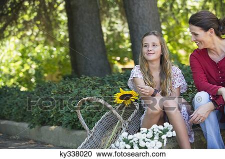 Little girl and mother sitting outdoors with flowers in the basket View Large Photo Image Stock Image - Little girl and mother sitting outdoors with flowers in the basket. Fotosearch