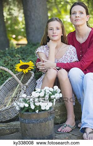Little girl and mother sitting outdoors with flowers in the basket View Large Photo Image Stock Photo - Little girl and mother sitting outdoors with flowers in the basket. Fotosearch