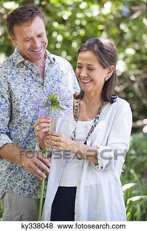 Stock Photo - Man giving flower to his mother and smiling. Fotosearch