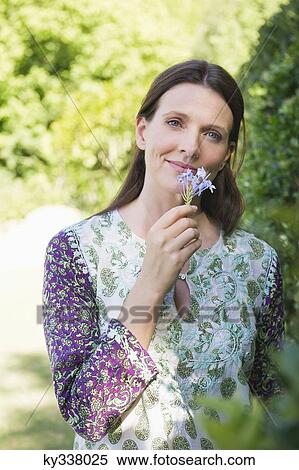 Portrait of a smiling mature woman smelling flowers in garden View Large Photo Image Stock Photography - Portrait of a smiling mature woman smelling flowers in garden. Fotosearch